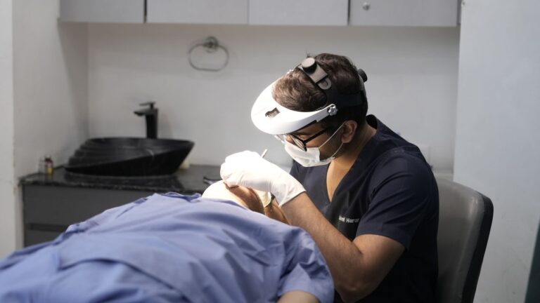 A dermatologist performing a procedure in a clinical setting.